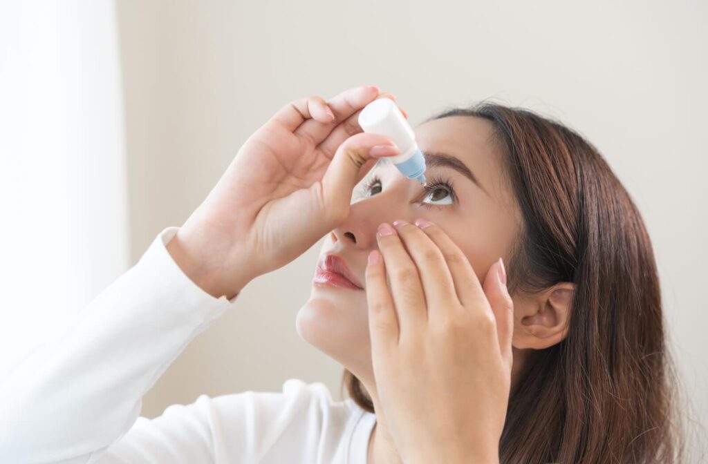 A person carefully applying eye drops, illustrating the use of Atropine eye drops as a treatment to slow the progression of nearsightedness (myopia) in patients.