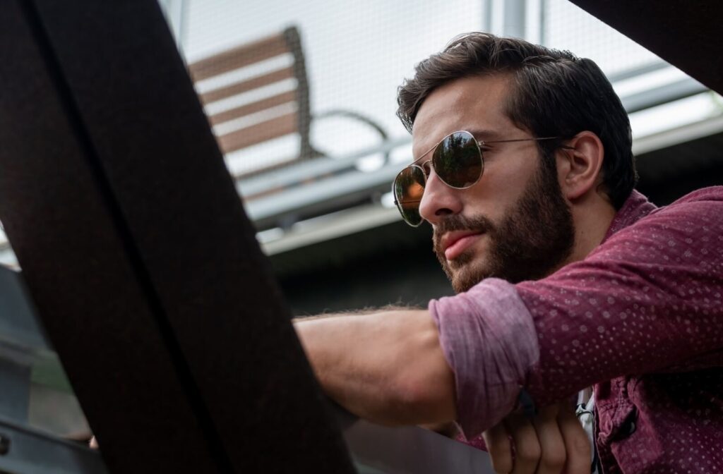 A profile view of an individual with a beard wearing classic aviator-style sunglasses.
